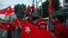 Supporters of the National League for Democracy (NLD) party wave flags in front of the party's headquarters in Yangon on November 9, 2020, as NLD officials said they were confident of a landslide victory in the weekend's election. (Photo by Ye Aung Thu / 