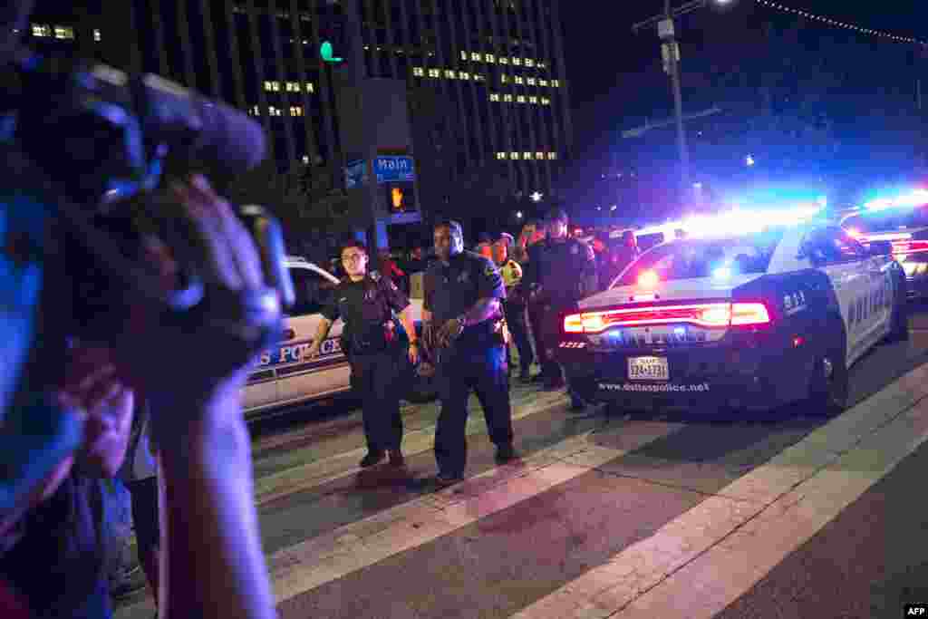 Bystanders stand near pollice baracades following the sniper shooting in Dallas on July 7, 2016.