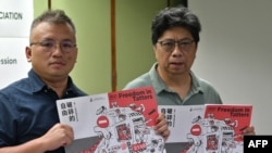香港记者协会主席陈朗升(左)与报告主笔杨振谦手持香港新闻自由年度报告《破碎的自由》。(2021年7月15日)