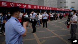 中国高考第一天,北京一处考场外警察和学校教师使用扩音器要求在外等候的考生家长遵守秩序。(2022月6月7日)