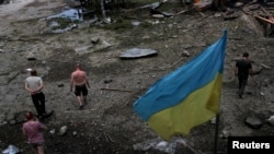 在俄罗斯进行的一次袭击之后，人们在乌克兰哈尔科夫郊外查看一处被毁坏的木仓库。(2022年6月3日)