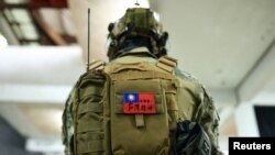 台湾新台北市一名市民背着写有“世界第一,台湾精神”的台湾旗帜的背包参加使用仿真枪的枪击和战斗技能训练。(2022年5月21日)