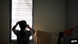 资料照片:一名缅甸钦族的难民女孩从吉隆坡市中心一间容纳了20多名寻求庇护者的小公寓的窗户向外张望。(2010年6月17日)