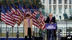 资料照片:在冲击国会大厦事件发生前举行的一次集会上,查普曼大学法学教授伊士曼(左)站在正在发言的前纽约市长朱利亚尼旁边。(2023年8月22日)