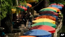 Sejumlah warga tampak berjalan di area Riverwalk di San Antonio, Texas, pada 17 Juni 2022, di tengah gelombang panas yang melanda negara bagian tersebut. (Foto: AP/Eric Gay)