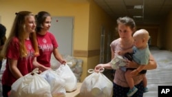 乌克兰东部顿涅茨克地区一名妇女带着孩子在领取当地政府提供的援助物资(2022年6月14日)