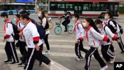 带着口罩的北京小学生穿过一条交通繁忙的十字路口。(美联社照片 2021年4月29日)