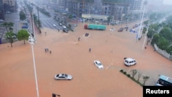 湖南长沙,大路积水,行人和车辆冒雨过马路(2017年7月1日)