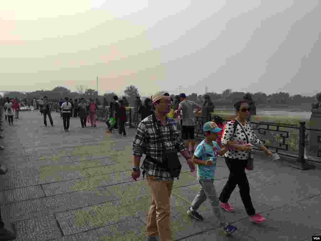 2016年10月2日,北京郊区卢沟桥上的一些行人没戴口罩,尽管当天上午8时北京市空气重污染应急指挥部办公室发布了空气重污染黄色预警。(美国之音叶兵拍摄)当局10月3日17时解除了这个预警,但仍有污染。