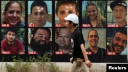 以色列特拉维夫一名男子走在10月7日哈马斯致命袭击中被绑架的人质海报前,下排左一为以色列裔美国人赫什·戈德堡-波林。(路透社:2024年9月1日)