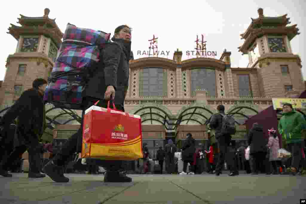 2018年2月9日,一名妇女在北京火车站外携带行李箱。下周农历新年假期前,数百万中国人乘坐火车,飞机和汽车旅行,春运高潮预计本周末开始。