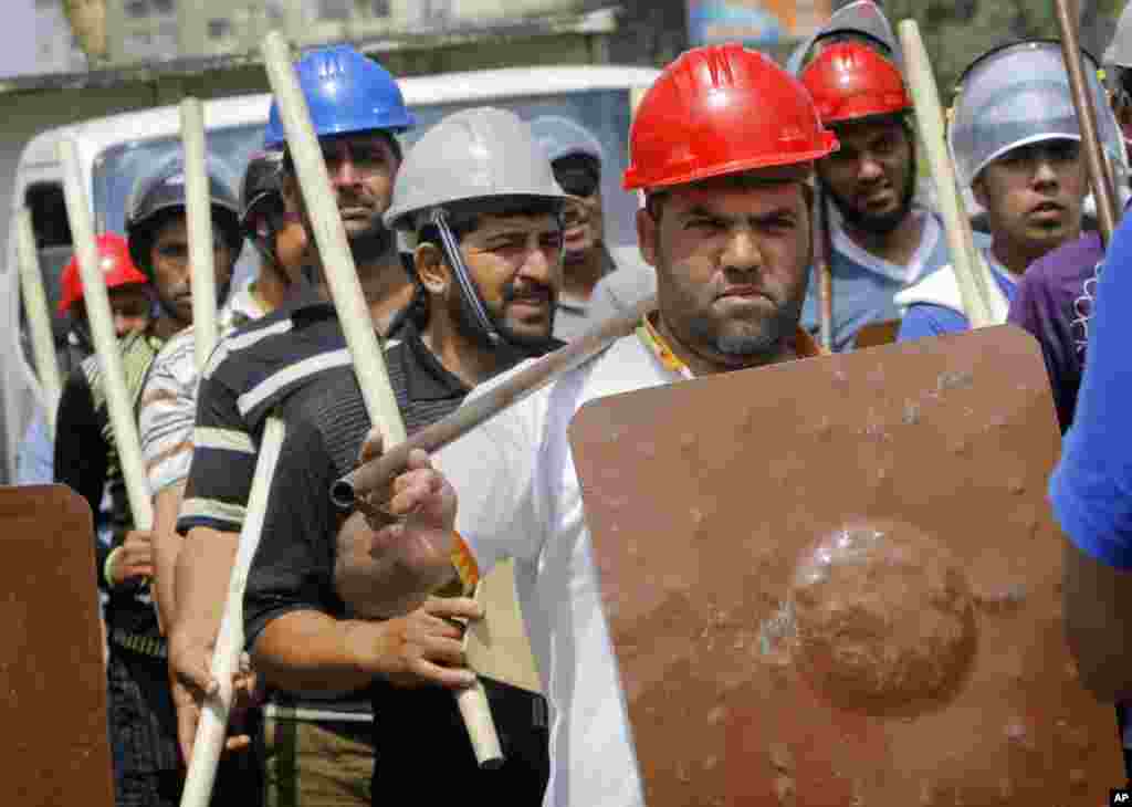 Người ủng hộ tổng thống Morsi cầm gậy gộc và mặc đồ bảo hộ bên ngoài nhà thờ Hồi giáo Rabia el-Adawiya gần dinh tổng thống ở Cairo, 2 tháng 7, 2013.