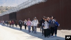 资料照片:一群来自中国寻求庇护的移民穿越美国与墨西哥边境后在加利福尼亚贾昆巴附近沿着隔离墙行走。(2023年10月24日)