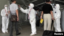 为防埃博拉,人们在进入广交会前接受体温检查。