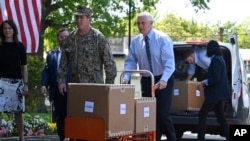 美国副总统迈克·彭斯(Mike Pence)在弗吉尼亚州亚历山大市的伍德宾康复和医疗中心(Woodbine Recovery And Healthcare Center)移动一辆手推车,车里装着来自联邦应急管理局(FEMA)的一箱箱个人防护用品。(2020年5月7日)