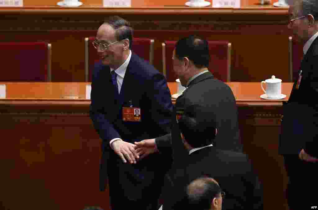 2018年3月5日,人大代表王岐山(左)在人大开幕式之后离开时与一位军方代表握手,这位戴着中央军委臂章的代表疑似范长龙。从照片上看,王岐山似乎急于走开。有消息说他是要找刚从美国回北京的刘鹤交谈。