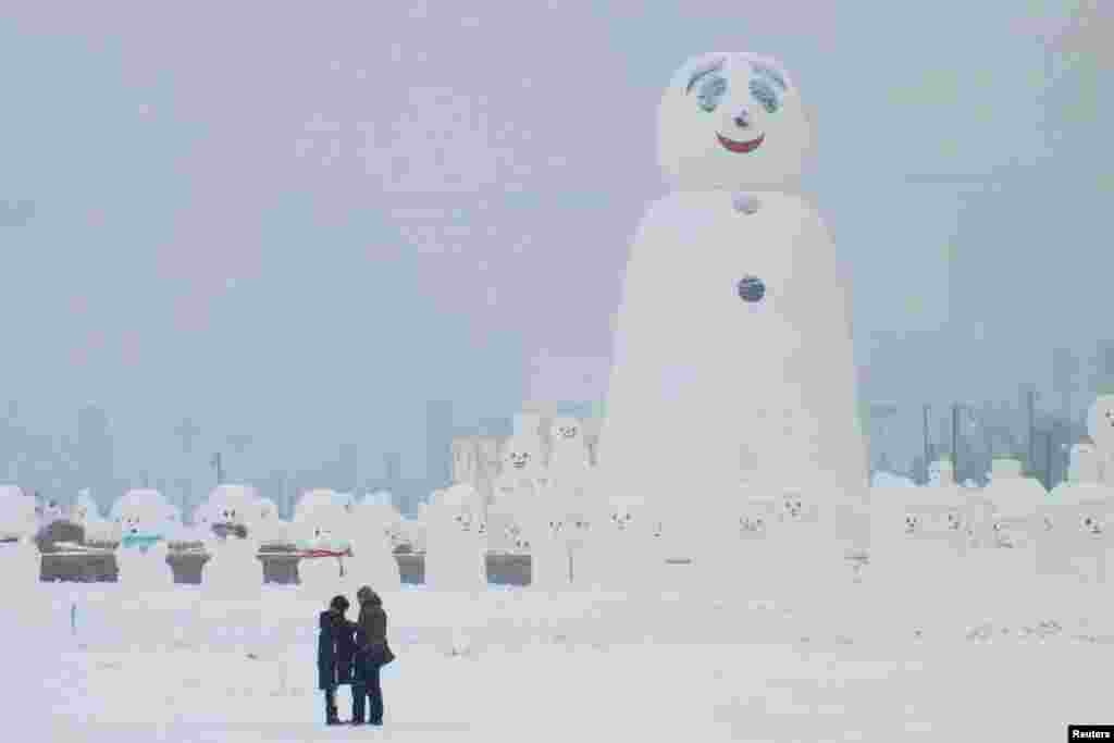 中国哈尔滨的国际冰雪雕塑节期间,大小雪人雪狗列队,一览游客小(2018年1月8日)