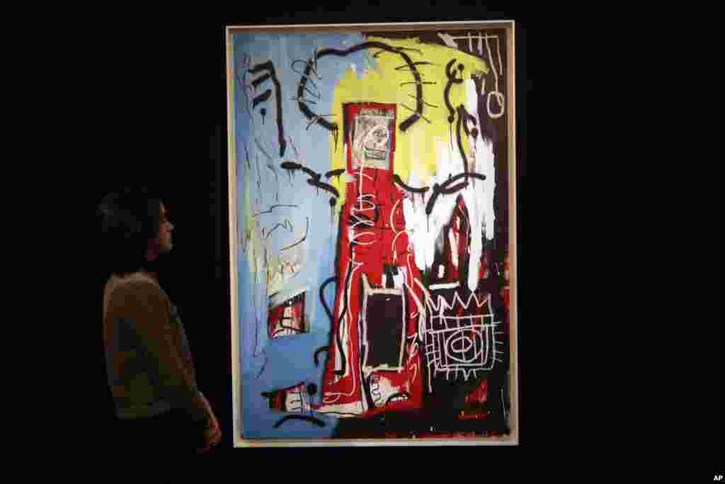 伦敦苏富比拍卖行的人员站在美国画家巴斯奎特(Jean-Michel Basquiat,有人翻译成巴斯奇亚)创作的油画《无题》(Untitled)旁边(2017年2月22日)。
