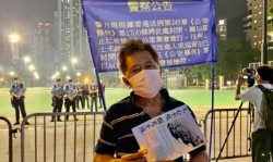 警方六四32周年纪念日引公安条例,围封原定支联会六四烛光集会场地维园足球场及草坪,有市民在警方警告横额前手持悼念六四的LED蜡烛 (美国之音/汤惠芸)