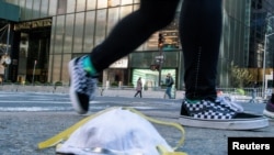 2020年3月14日,一名女子从特朗普大厦附近街面上一个用过的防护口罩旁走过。