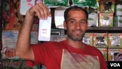 印度迈索尔一位集市摊主向记者展示他心爱的小米手机。(美国之音朱诺拍摄,2015年12月4日)