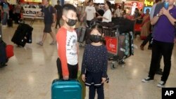 资料照:戴着口罩的儿童从武汉抵达悉尼机场。(2020年1月23日)