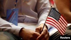 一名新公民在纽约公共图书馆的公民宣誓仪式上手持美国国旗(2018年7月3日)