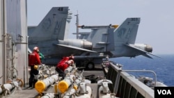 2017年3月3日在南中国海进行例行巡航前,美国航母卡尔·文森号上的海军人员准备给F-18战斗机加装导弹。