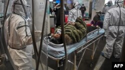 身穿防护服的医务人员在武汉红十字医院运送一名病人。(2020年1月25日)