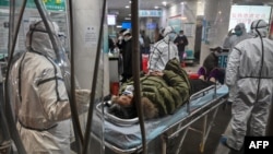 身穿防护服的医务人员在武汉红十字医院运送一名病人。(2020年1月25日)