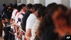 萨尔瓦多一名反帮派团伙部队警察看押着一批在警方突袭行动中抓捕的MS-13团伙成员。(资料照片)