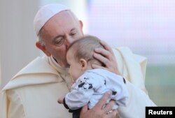 罗马天主教教宗方济各在圣彼得广场亲吻一名婴儿。(2018年9月12日)