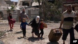 当伊拉克特种部队于2017年5月17日在伊拉克摩苏尔城西部与伊斯兰国家武装分子作战时,一名女孩与她的兄弟在逃离该街区。