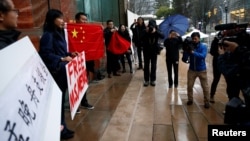 在加拿大不列颠哥伦比亚省一家正在审理孟晚舟案的法院外手举中国国旗和标语牌的孟晚舟支持者。(2018年12月11日)