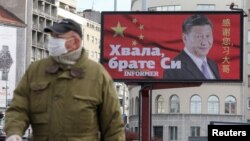 塞尔维亚一名戴着口罩的男子走过贝尔格莱德街头树立的感谢中国领导人习近平的广告牌旁。(2020年4月1日)