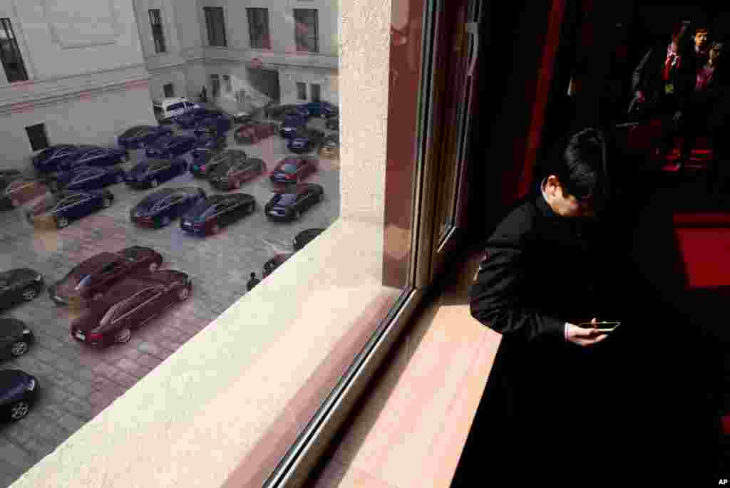 2013年3月5日中国在北京举行第十二届人大开幕式之后,当政府官员的车辆准备离开人民大会堂的时候,一名人大代表查看他的手机。