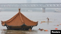 在被洪水淹没的武汉长江旁的一个只露出顶部的亭子边有武汉民众在游泳。(2020年7月8日)