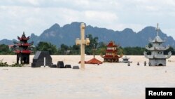 Những ngôi mộ bị ngập tại một ngôi làng bị lụt do mưa lớn gây ra bởi bão nhiệt đới Son Tinh ở tỉnh Ninh Binh, Vietnam, ngày 22/7/2018. REUTERS/Kham
