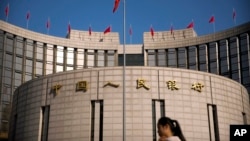 资料照片:2017年3月10日,一位女性在中国人民银行大楼前走过。