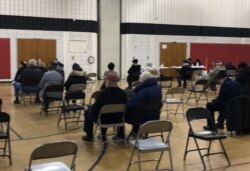 资料照片:在马里兰州蒙哥马利郡的一处新冠疫苗接种中心,以老年人为主的民众在接种疫苗之后坐在观察区内。(2021年2月21日)