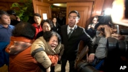 失踪马航班机一名中国乘客的亲属在北京听到最新消息后失声痛哭并瘫倒。(2014年3月24日)