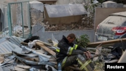 在乌克兰西部城市利沃夫,在俄罗斯导弹和无人机袭击了居民楼之后,一名救援人员坐在空袭废墟现场。(2024年9月4日)
