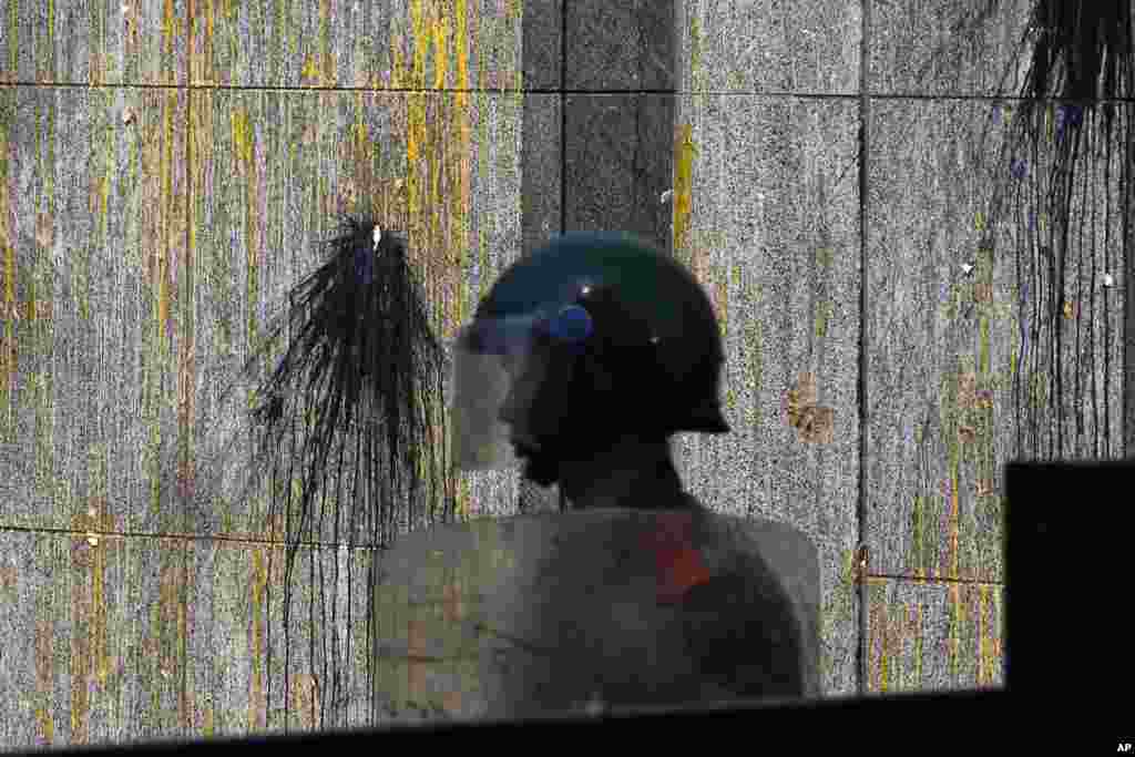 Cảnh sát bán quân sự bảo vệ cổng vào Đại sứ quán Nhật Bản ở Bắc Kinh, bên cạnh là bức tường bị dính đầy sơn và trứng, ngày 16/9/2012