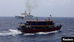 资料照:一艘菲律宾补给船在为驻扎在南中国海搁浅的菲律宾军舰执行补给任务时驶过一艘中国海警船。(2023年10月4日)