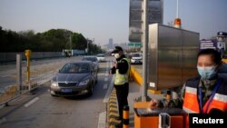 资料照:在新冠疫情爆发武汉实行交通管制后,一名警察在一个高速收费站指挥交通。(2020年4月8日)