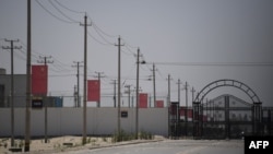 新疆和田一处据信为关押着维吾尔穆斯林少数民族的集中营设施外沿路高挂中国国旗。(2019年5月31日)