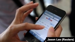 资料照:中国北京的一位手机用户用智能手机上搜索网站百度