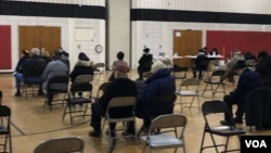 资料照片:在马里兰州蒙哥马利郡的一处新冠疫苗接种中心,以老年人为主的民众在接种疫苗之后坐在观察区内。(2021年2月21日)