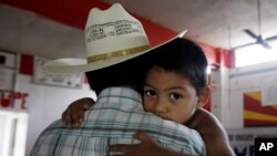 三岁的米古尔紧紧搂着他的父亲。他的父母是非法移民,因为儿子米古尔出生在美国德克萨斯州而留在美国。(资料照片)