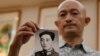 2020年10月16日武汉新冠肺炎死者的亲属张海拿着他病逝的父亲年轻时拍摄的照片。
